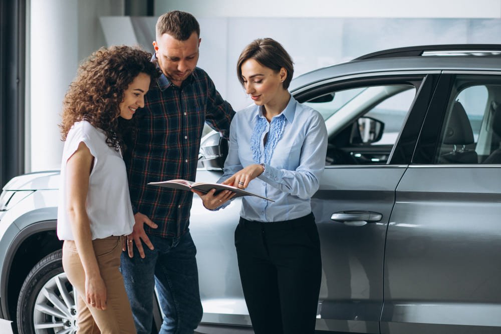 jovem-casal-conversando-com-uma-pessoa-de-vendas-em-um-showroom-de-carros